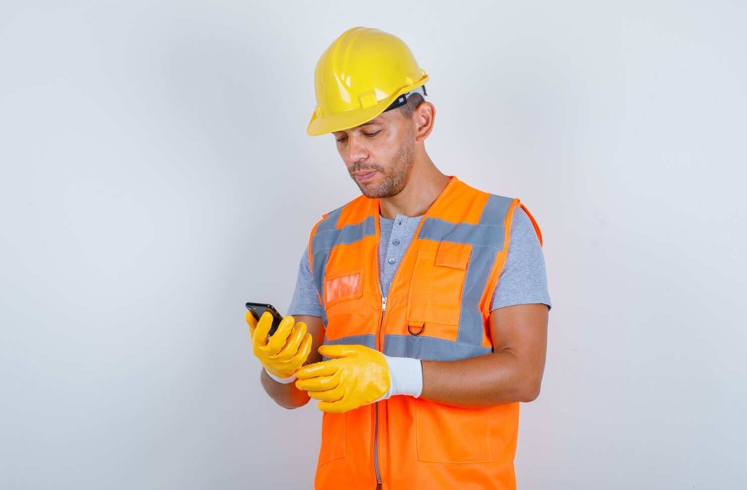 constructor masculino uniforme casco guantes telefono movil mirando ocupado vista frontal 176474 10056